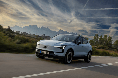 Een moderne elektrische auto rijdt op een schilderachtige weg in Vlaanderen, met een bergachtig landschap en een dynamische lucht op de achtergrond. Dit beeld illustreert de groeiende populariteit van elektrische voertuigen en de impact van subsidies op duurzame mobiliteit.