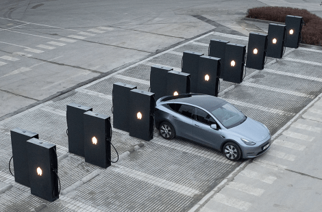 Een zilvergrijze elektrische auto parkeert bij een rij van laadstations op een openbare parkeerplaats, namelijk de Smappee EV Ultra.